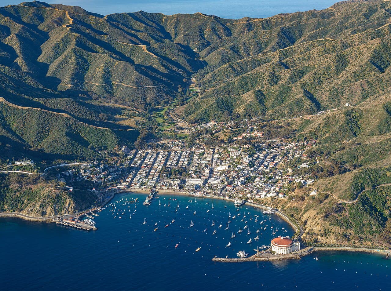 Avalon, California — Morning aerial photograph of Avalon on Santa Catalina Island, California. The circular Catalina Casino, recognizable by its red tile roof, stands prominently on the waterfront at the lower right, photo by Don Ramey Logan